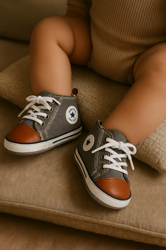 Detaljerad babysneaker i grå / brun färg. Bild tagen framifrån på en bebis. Bebisskor, babyskor
